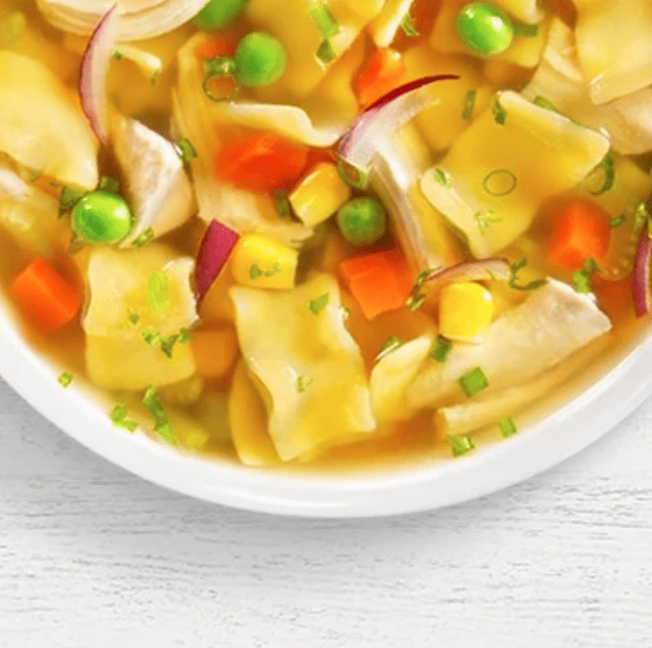 A bowl of soup with vegetables and noodles.