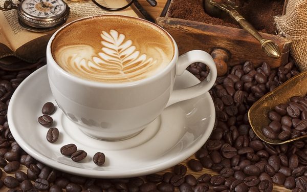 A cup of coffee with a leaf design on it.