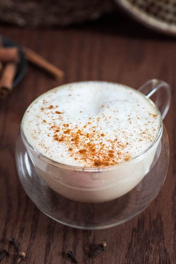 A cup of coffee with cinnamon on top.