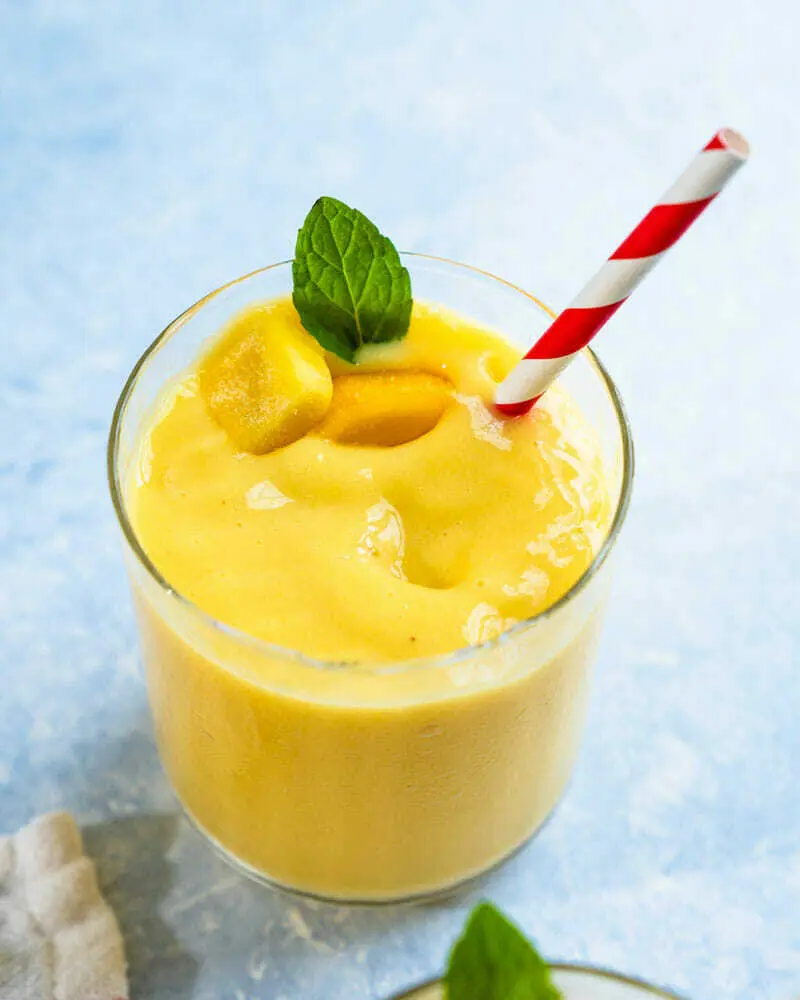 A glass of orange juice with a straw.
