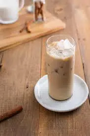 A glass of iced coffee on a plate.