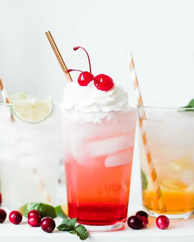 A close up of a drink with whipped cream and cherries