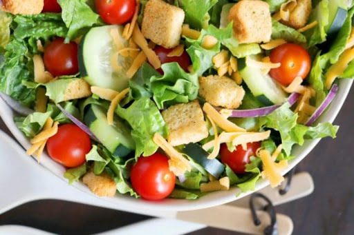 A salad with tomatoes, lettuce and croutons.