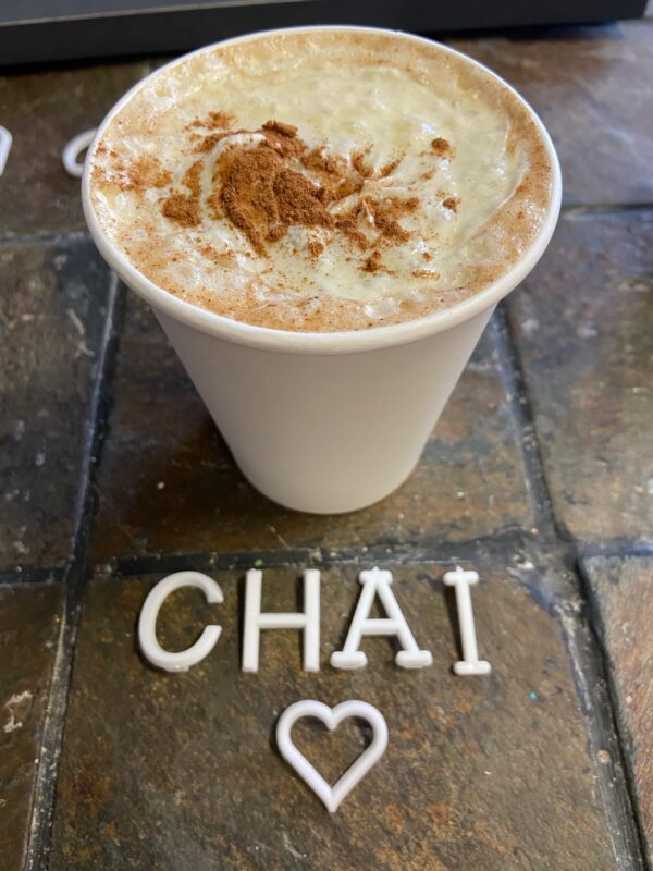 A cup of coffee with the word " chai " written in white letters.