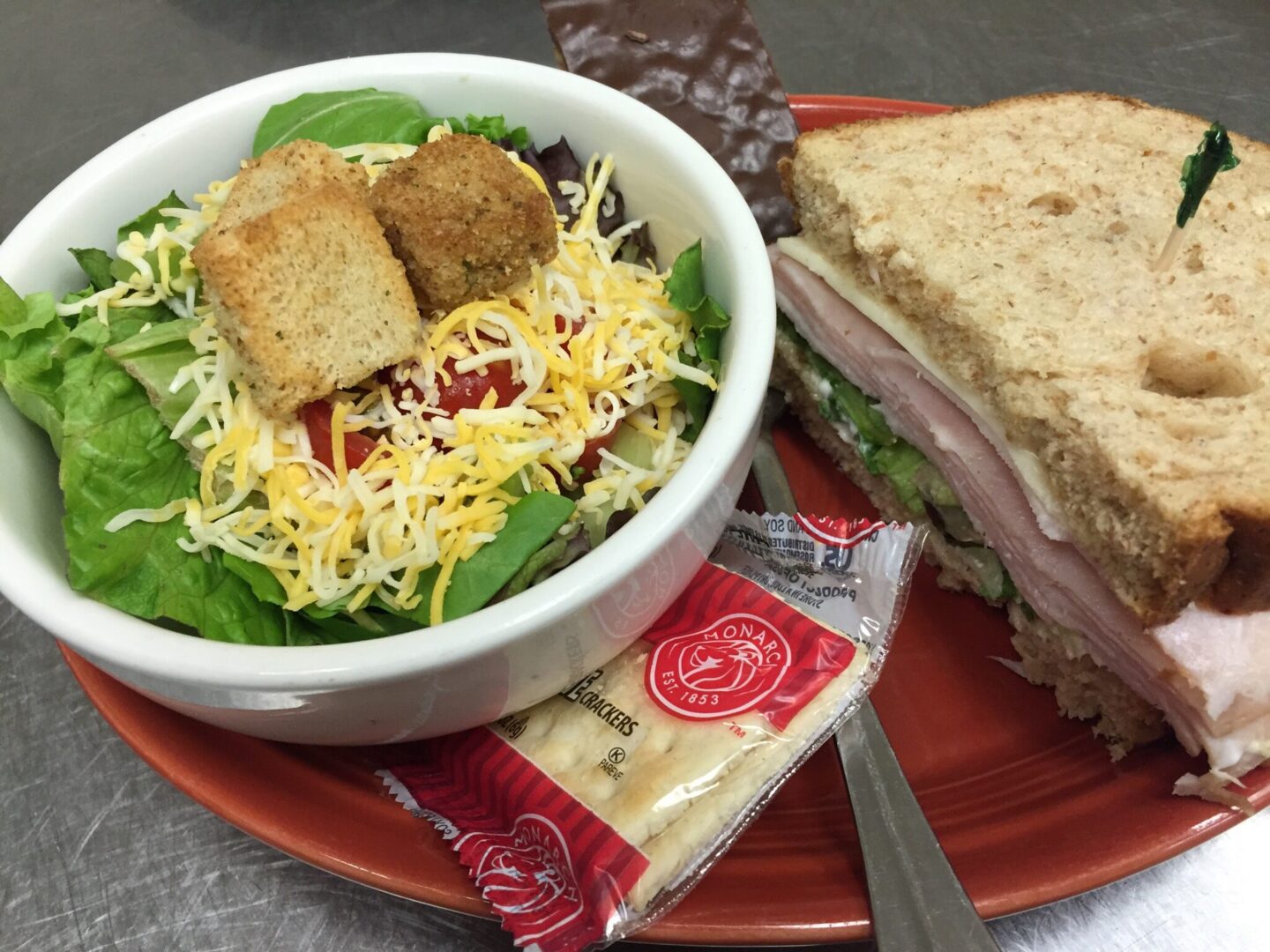 A bowl of salad and sandwich on a plate.