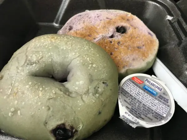 Green and purple bagels with cream cheese.