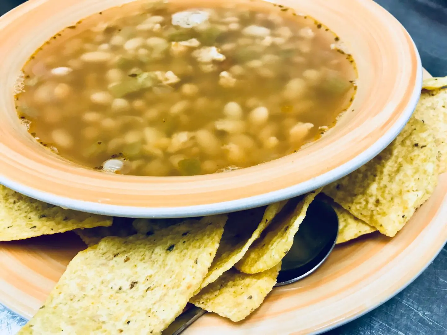 A bowl of soup and some tortilla chips on the table.