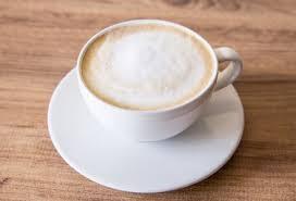 A cup of coffee on top of a white plate.