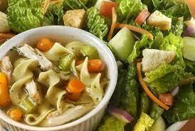 A bowl of soup and salad are on the table.