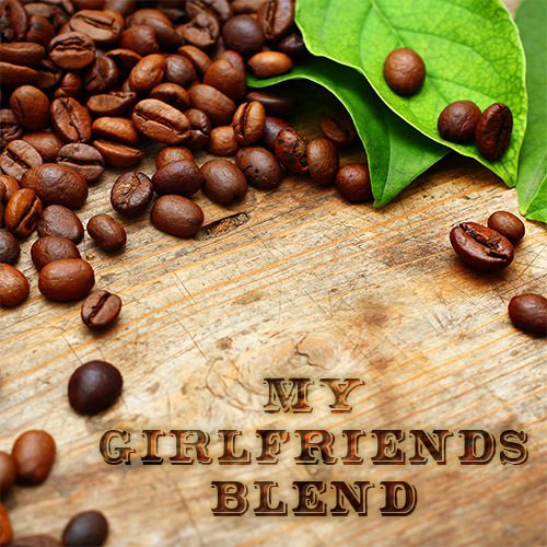 A wooden table topped with coffee beans next to green leaves.
