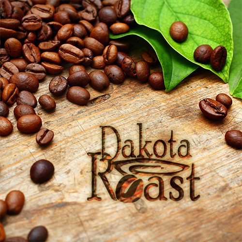 A wooden table topped with coffee beans next to green leaves.