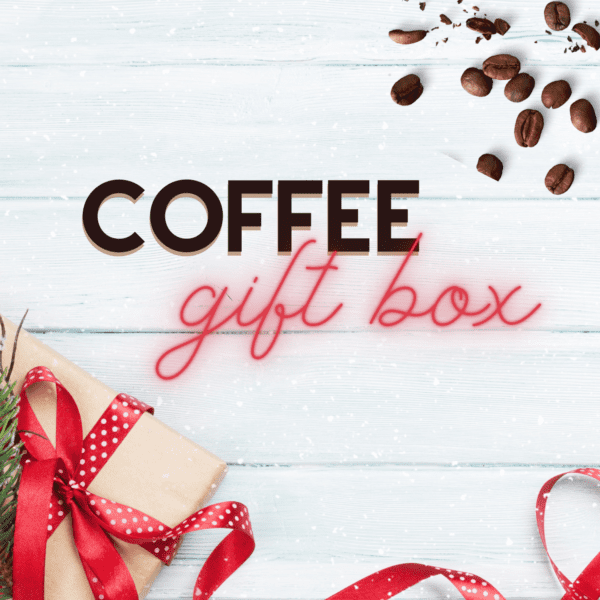 A festive coffee-themed gift arrangement featuring the "Coffee Gift Box & Subscription" text, coffee beans, a wrapped present adorned with a red ribbon, and greenery on a white wooden background.