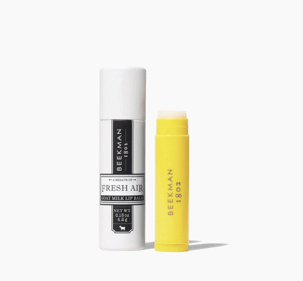 A yellow tube of lip balm next to a white container.