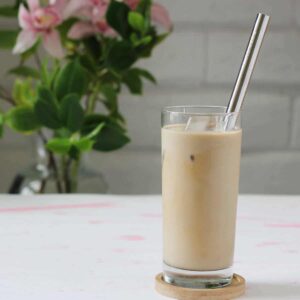 A glass of milk with a straw on the side.