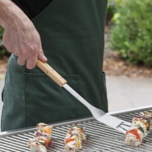A person holding a spatula and some food on the grill.