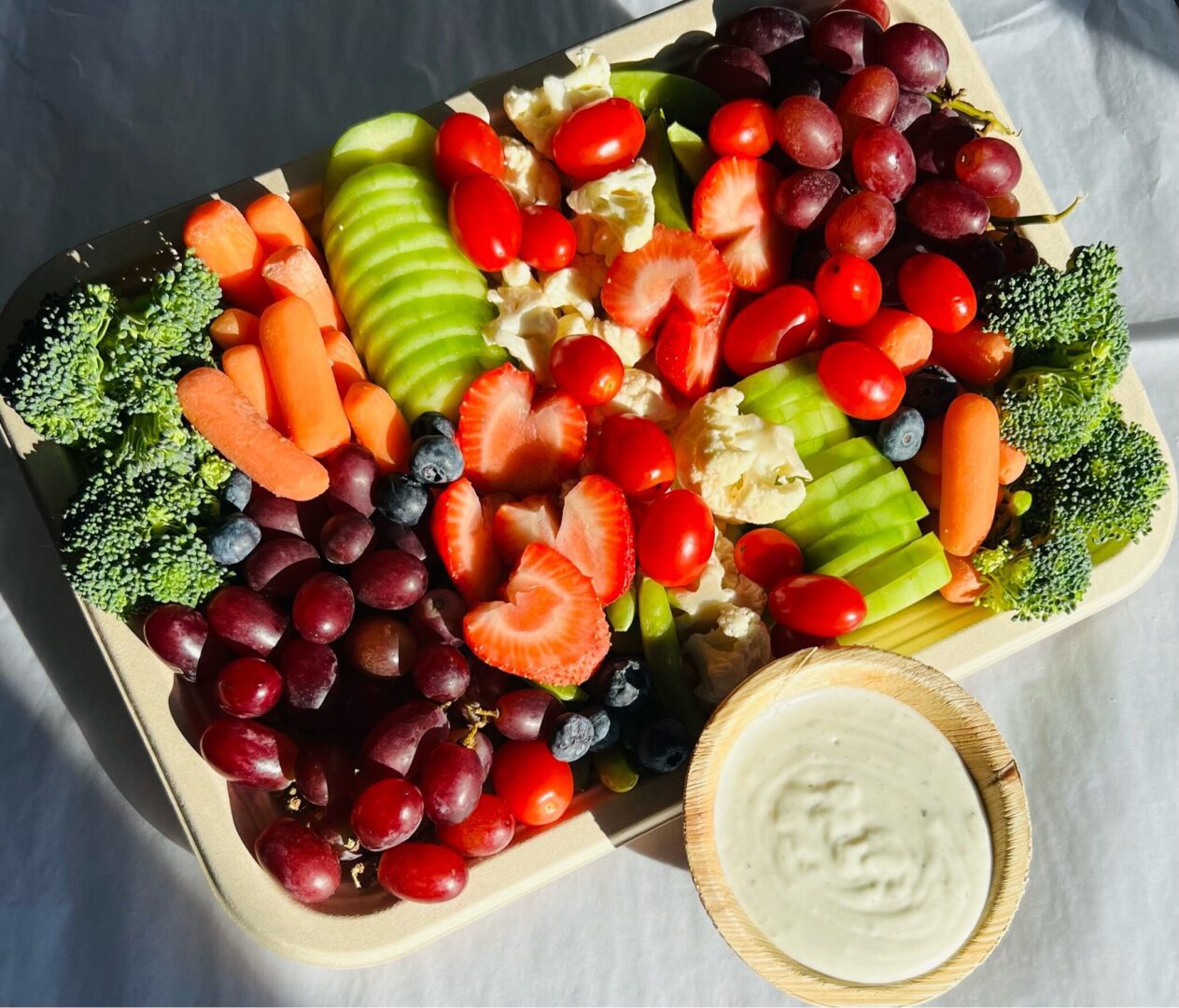 A tray of fruit and dip on the table.
