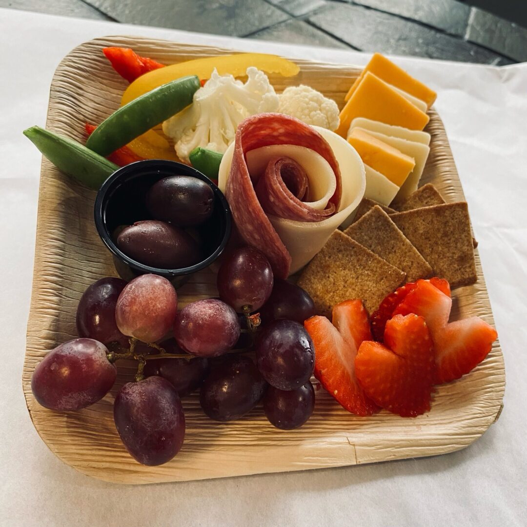 A wooden tray with grapes, crackers and cheese.