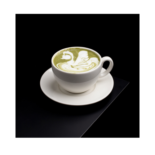 Matcha latte with swan latte art on a saucer, resting on a black surface.