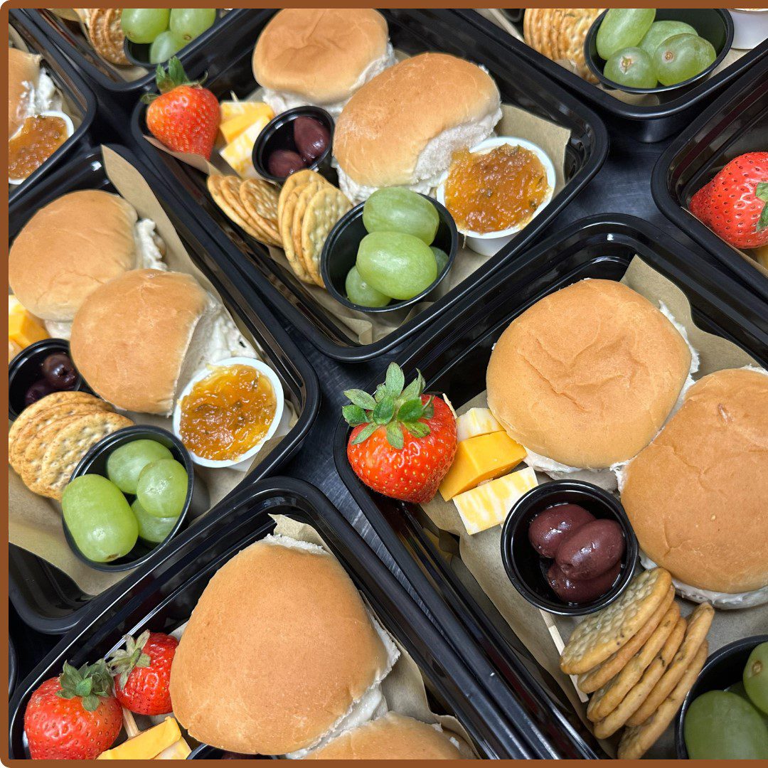 charcuterie lunch boxes A tray of food with sandwiches and fruit.