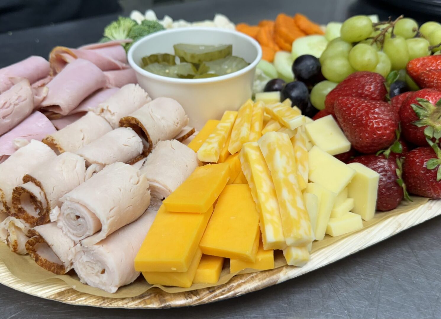 A plate of food with ham, cheese and fruit.