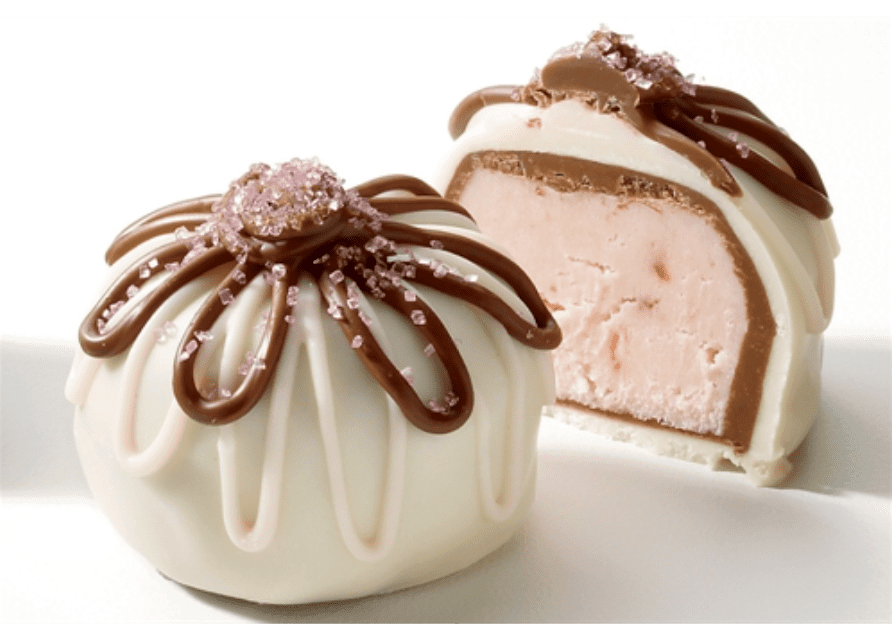 A whole and a half chocolate-coated dessert with white icing, a pink filling, and a drizzle of chocolate, topped with pink sugar crystals.
