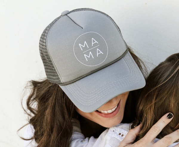 A person wearing a gray cap with the word "MAMA" hugs a child.