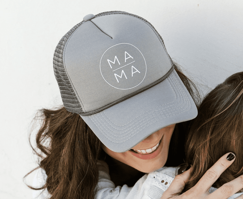 A person wearing a gray cap with the word "MAMA" hugs a child.