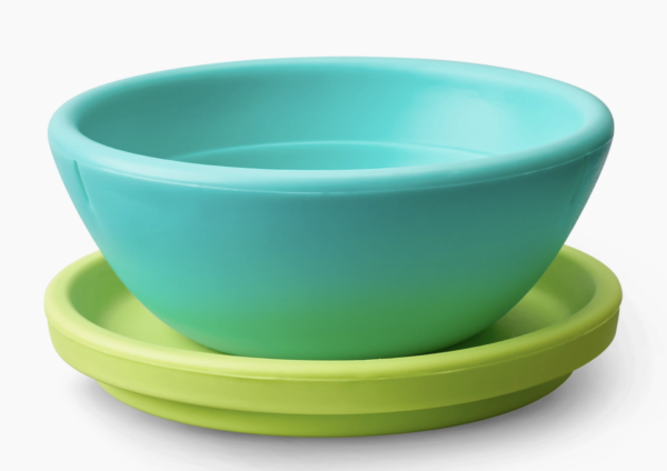 A light blue bowl sits atop a green saucer on a white background.