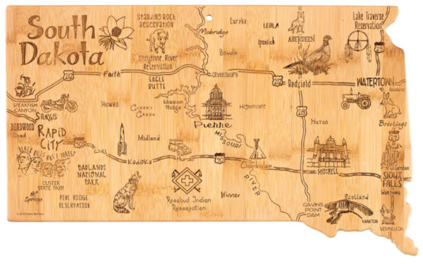 A wooden map of South Dakota featuring illustrations of landmarks, cities, and wildlife, including Mount Rushmore, Badlands National Park, and a bison.