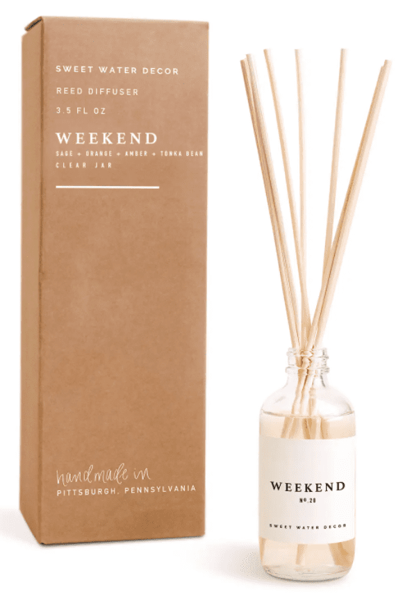 Reed diffuser labeled "Weekend" with sage, orange, amber, and tonka bean scent. It is beside its brown box packaging stating it is handmade in Pittsburgh, Pennsylvania.