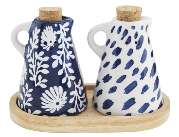 Two ceramic oil and vinegar cruets with cork stoppers and blue floral and spotted patterns, placed on a wooden tray.
