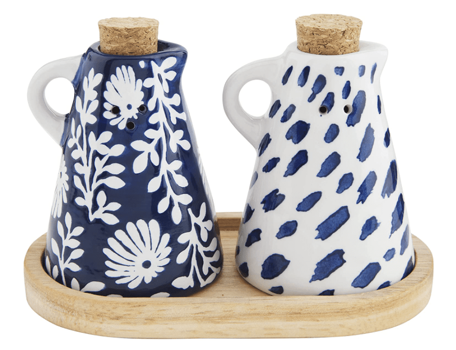 Two ceramic oil and vinegar cruets with cork stoppers and blue floral and spotted patterns, placed on a wooden tray.