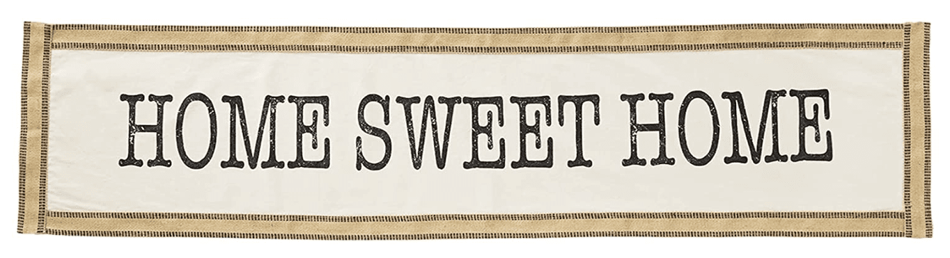 A fabric banner with the text "HOME SWEET HOME" in bold, black letters on a white background with a tan border.