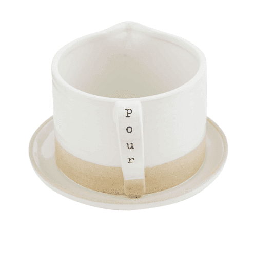 White ceramic pour-over coffee dripper with a handle labeled "pour," placed on a matching saucer.
