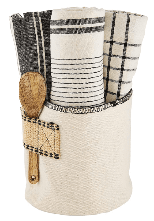 A beige fabric holder containing three rolled kitchen towels with black stripes and a wooden spoon in an attached pocket.