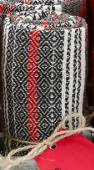 A rolled woven fabric with black, red, and white geometric patterns, tied with string.