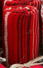Close-up of a rolled red and black woven textile with white geometric patterns.