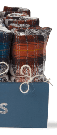 Close-up of rolled plaid fabrics in various colors, tied with thin string and standing upright in a blue container.