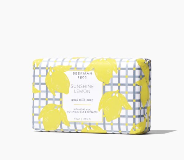 Rectangular bar of Beekman 1802 Sunshine Lemon goat milk soap, wrapped in lemon-patterned paper with a plaid background.