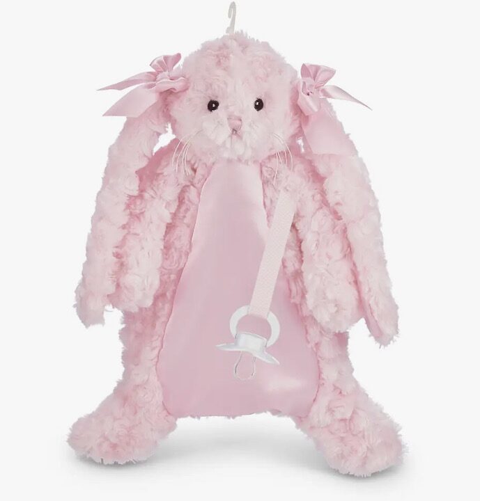 A plush pink bunny backpack with bows on its ears and a pacifier detail on the front.
