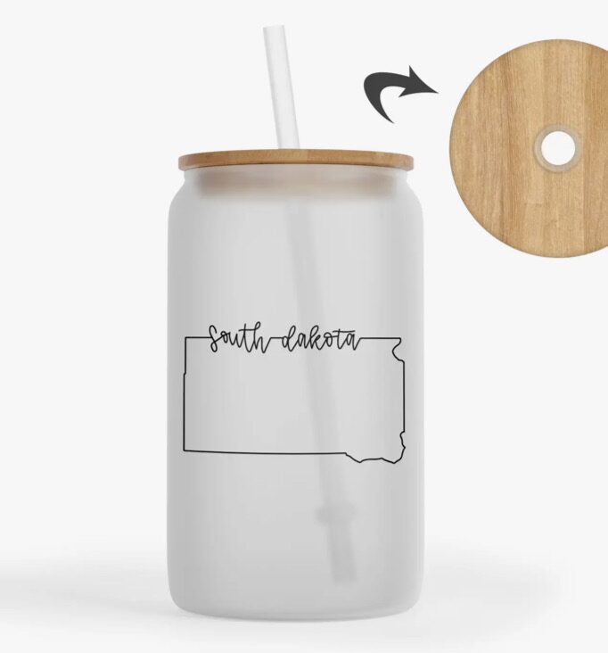 Frosted glass tumbler with straw, wooden lid, and "South Dakota" text overlaying a state outline.