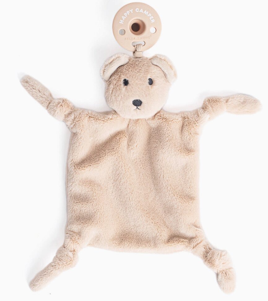 A beige plush bear-shaped pacifier holder with a softly textured square body and outstretched arms and legs.