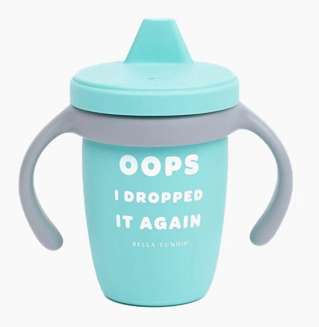 A teal sippy cup with a gray handle and a humorous message, "Oops I Dropped It Again," printed in white text.