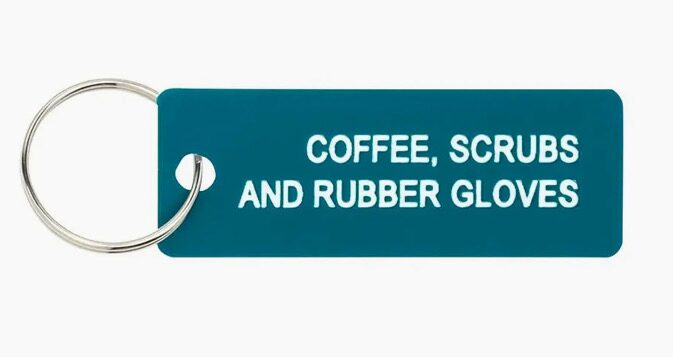 A teal keychain with the text "COFFEE, SCRUBS AND RUBBER GLOVES" written in white.
