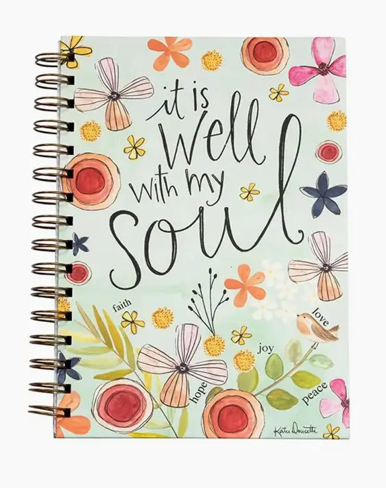 A floral spiral notebook cover with the phrase "it is well with my soul" and words like faith, hope, joy, love, peace.