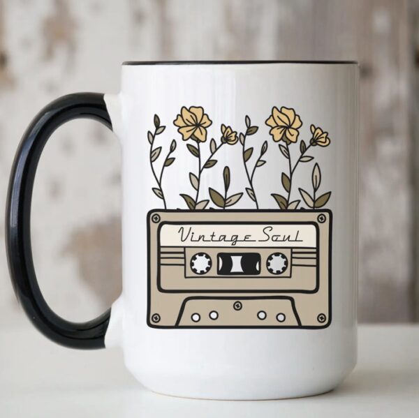 White mug with a black handle featuring a design of a cassette labeled "Vintage Soul" with yellow flowers growing from the top.
