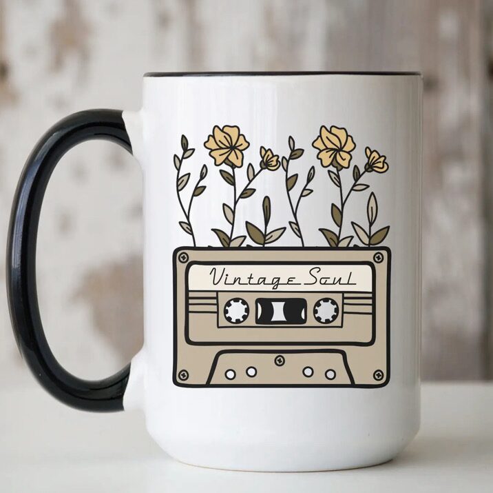 White mug with a black handle featuring a design of a cassette labeled "Vintage Soul" with yellow flowers growing from the top.