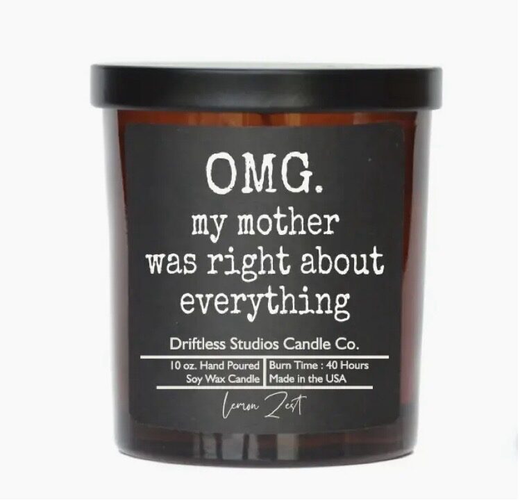 A candle with a humorous label reading "OMG. my mother was right about everything" from Driftless Studios Candle Co. Burn time: 40 hours, 10 oz. lemon zest scent, hand poured, soy wax.
