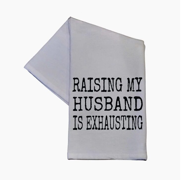 White kitchen towel with the text "Raising my husband is exhausting" printed in black.