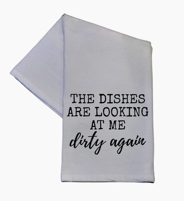 White dish towel with black text saying, "The dishes are looking at me dirty again.